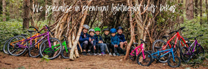   A group of young cyclists gather together in the forest in a den made out of branches with their Forme Cubley and Kinder bikes close by. 