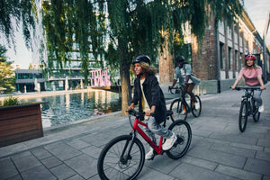 Group photo with lead girl cycling on a Woom EXPLORE 5 red bike.