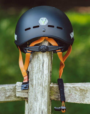 YOMO matt dark grey kids' helmet perched on a wooden post against a blurred, natural background.