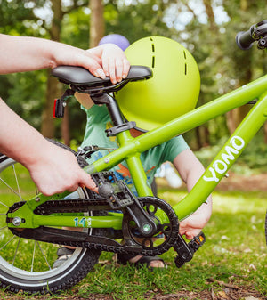Child wearing a YOMO matt green kids' helmet with a YOMO 14 green bicycle.