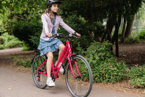 Girl cycling on her Frog City 67 pink 26 inch wheel 8 speed lightweight city bike.