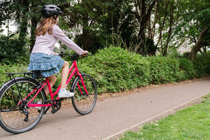 Girl cycling on her Frog City 67 pink 26 inch wheel 8 speed lightweight city bike.