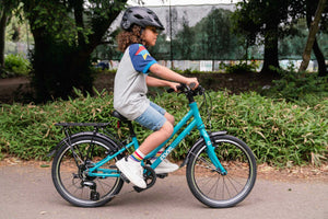 Girl cycling on her Frog City 53 teal 20 inch wheel 8 speed lightweight city bike.
